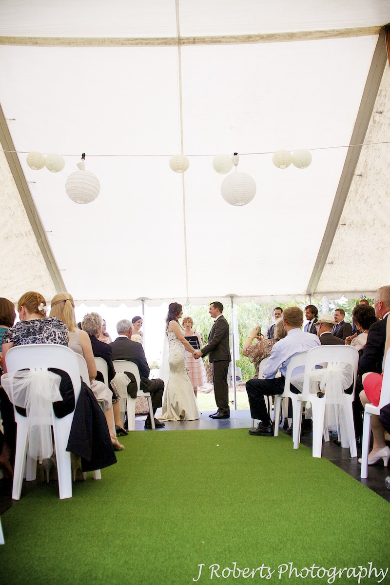 Bride and groom hold hands at head of aisle in outdoor garden wedding - wedding photography sydney
